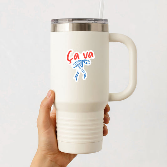 White insulated mug with 'Ca va' design held by a hand on a white background