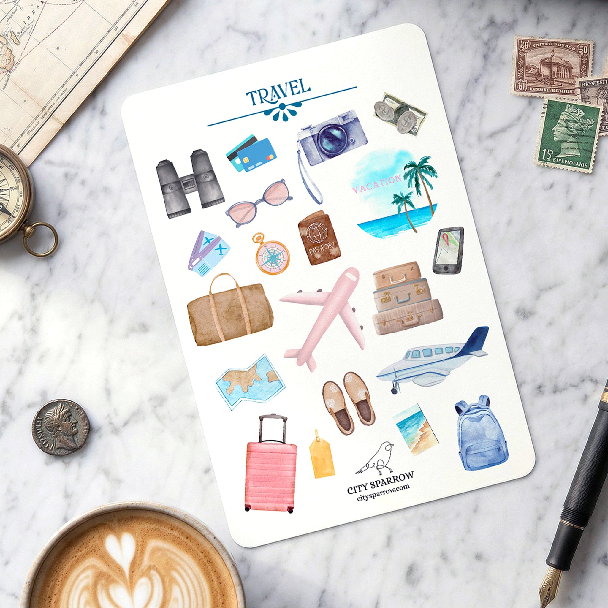 Sheet of travel-themed stickers on a marble surface with a cup of coffee, pen, and map.