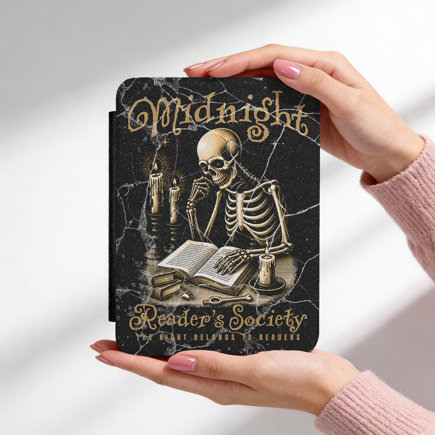 Kindle case with skeleton design and 'Midnight Reader's Society' text held by a person.