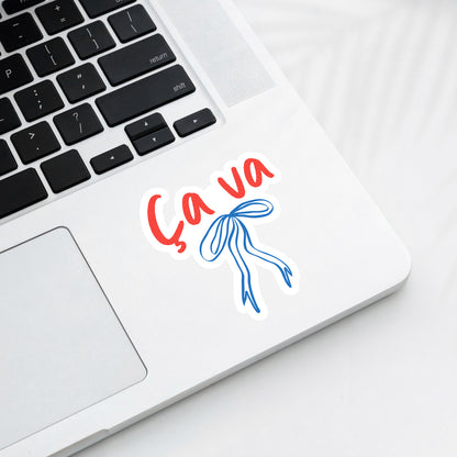 Laptop with 'Ca Va' sticker on a white surface
