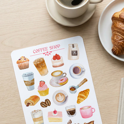 Sheet of coffee shop-themed stickers with a cup of coffee and croissant on a wooden table.