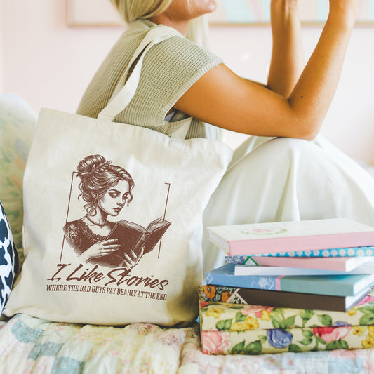 Person holding a tote bag with a literary design of a woman reading a book and a stack of books on a couch.