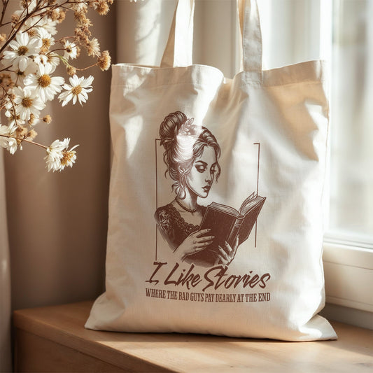 Tote bag with a design of a woman holding a book and text 'I Like Stories' on a wooden surface with flowers.