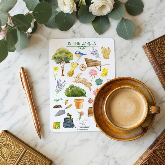 Sticker sheet with garden-themed illustrations on a marble surface with a cup of coffee and pen.