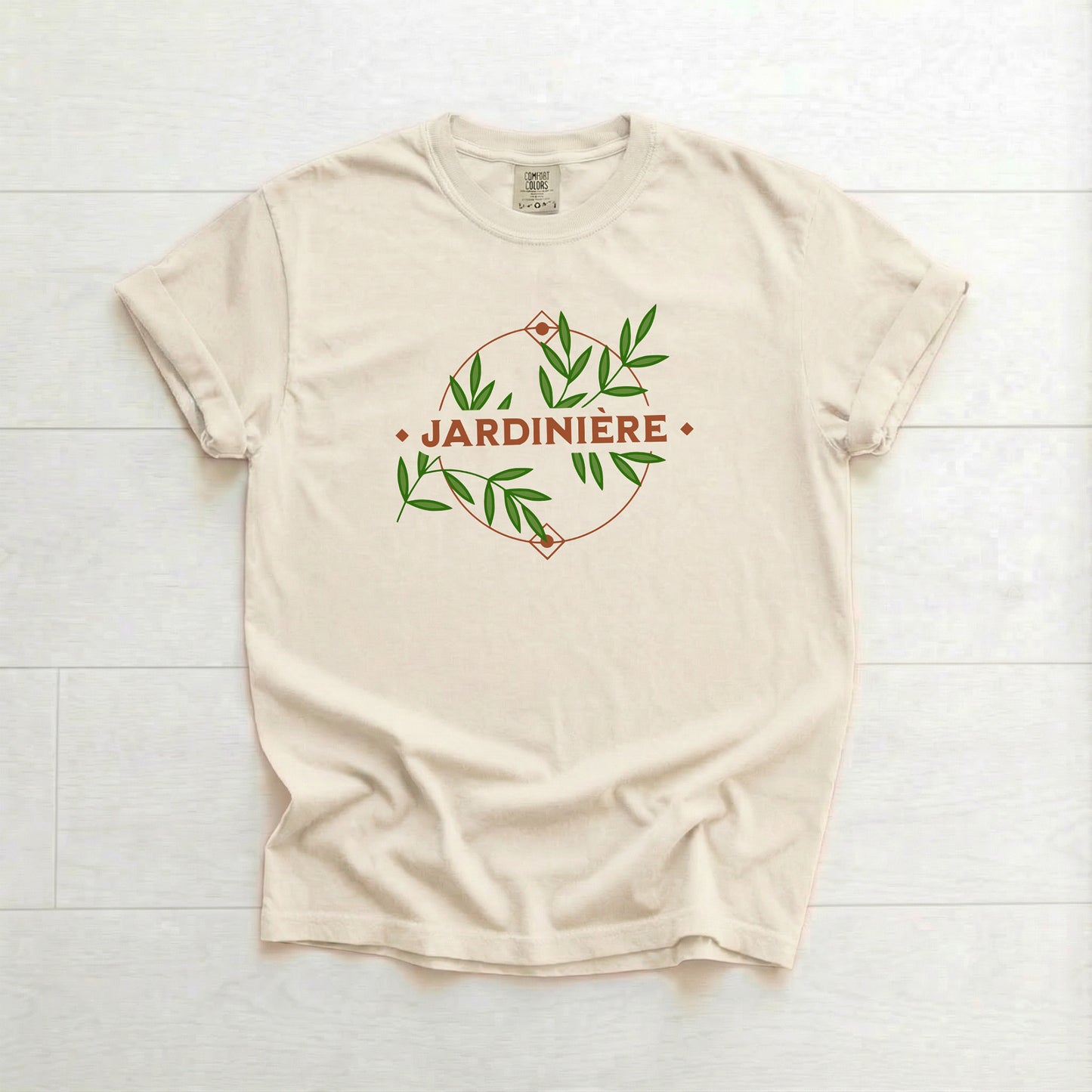 Beige t-shirt with 'Jardinière' design on a white wooden surface