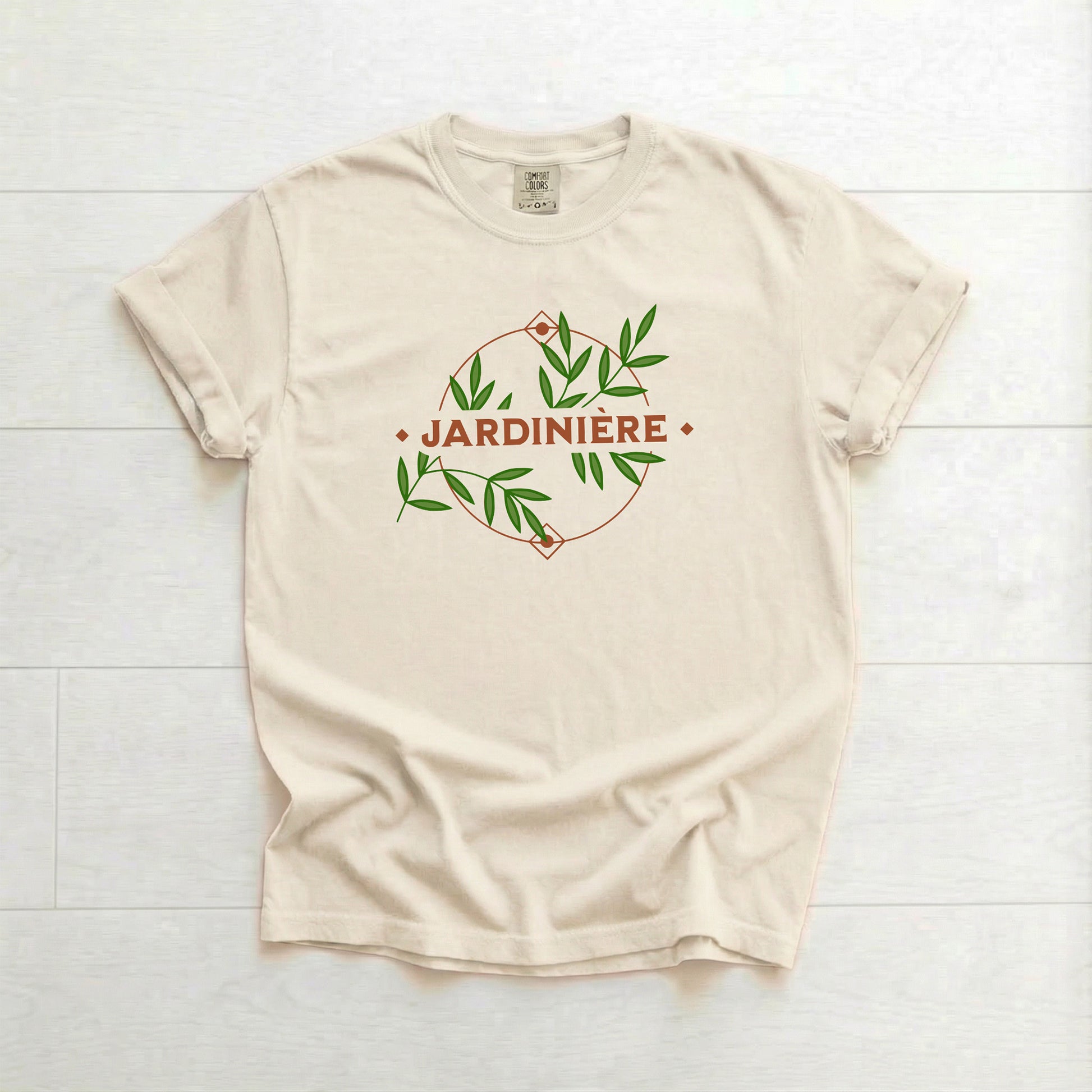 Beige t-shirt with 'Jardinière' design on a white wooden surface