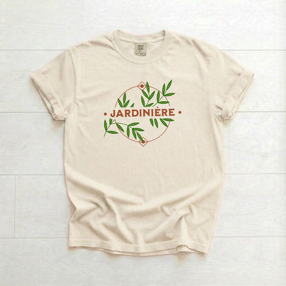 Beige t-shirt with 'Jardinière' design on a white wooden surface