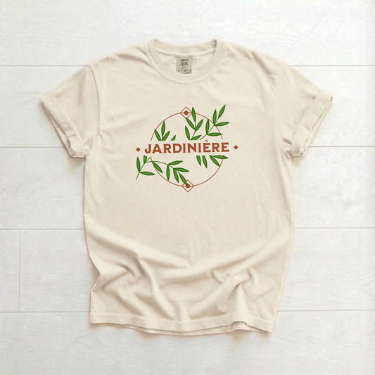 Beige t-shirt with 'Jardinière' design on a white wooden surface