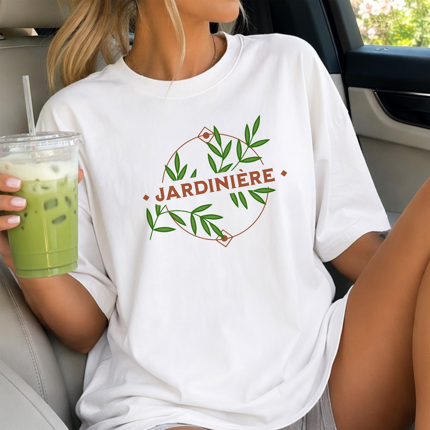 A woman wearing a white t-shirt with 'JARDINIÈRE' design, holding a drink.