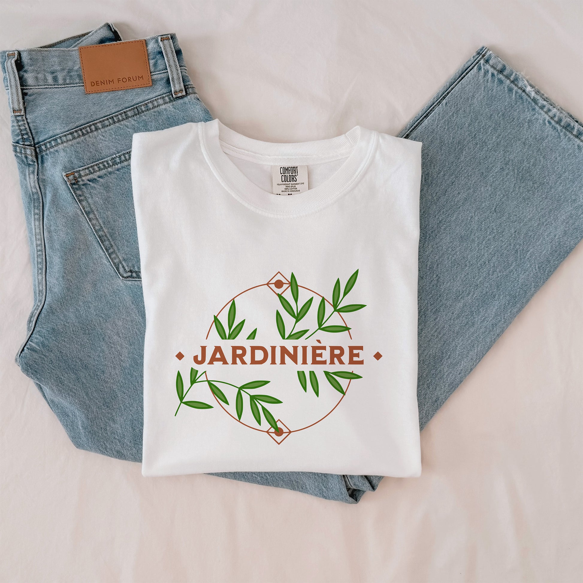 White t-shirt with 'JARDINIÈRE' design on a pair of blue jeans