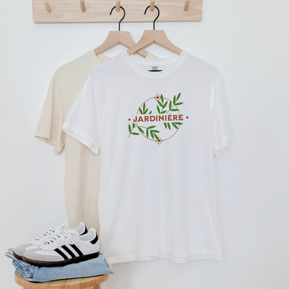 White t-shirt with 'Jardinière' design, beige sweater, and sneakers on a white background