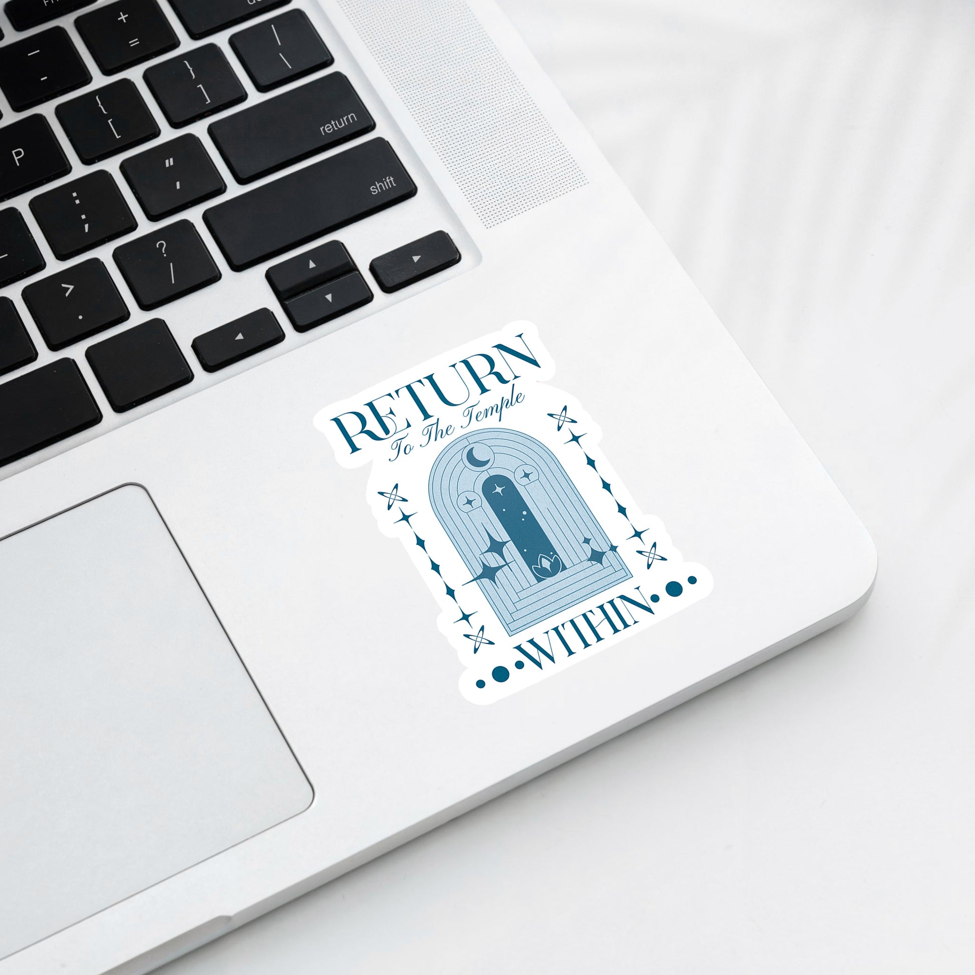 Laptop with a sticker on the palm rest area featuring text and a temple design.