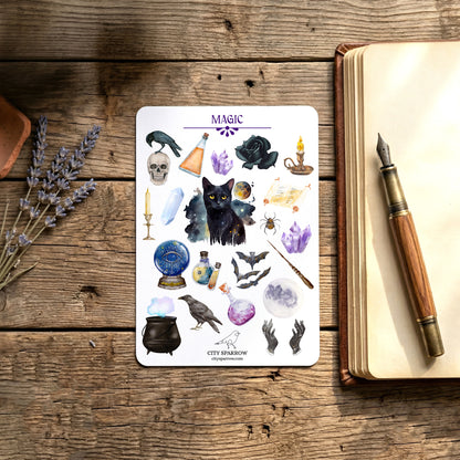 Sheet of stickers with mystical designs on a wooden surface next to an open book and pen.