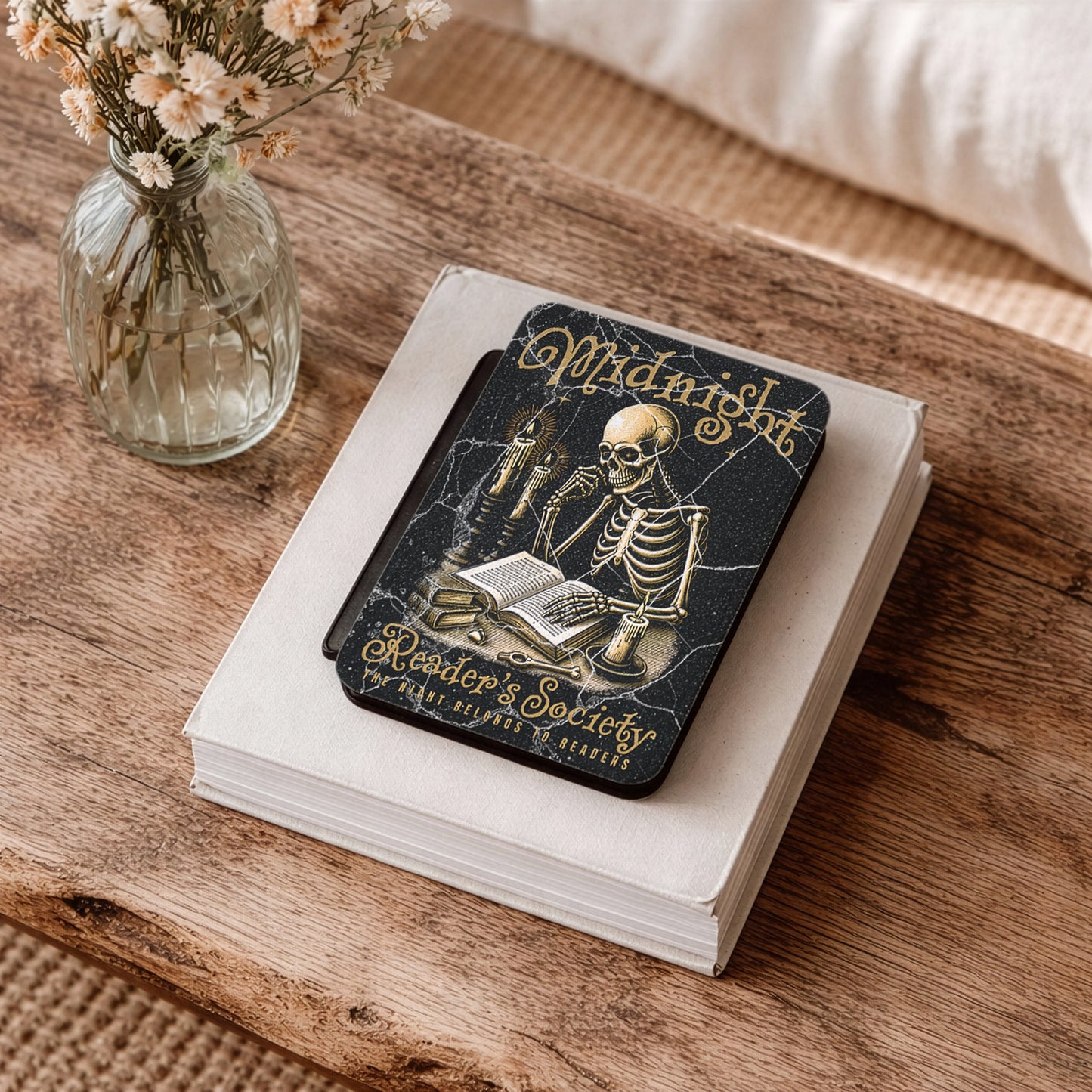 Kindle eReader case with skeleton design on a book on a wooden surface with flowers.