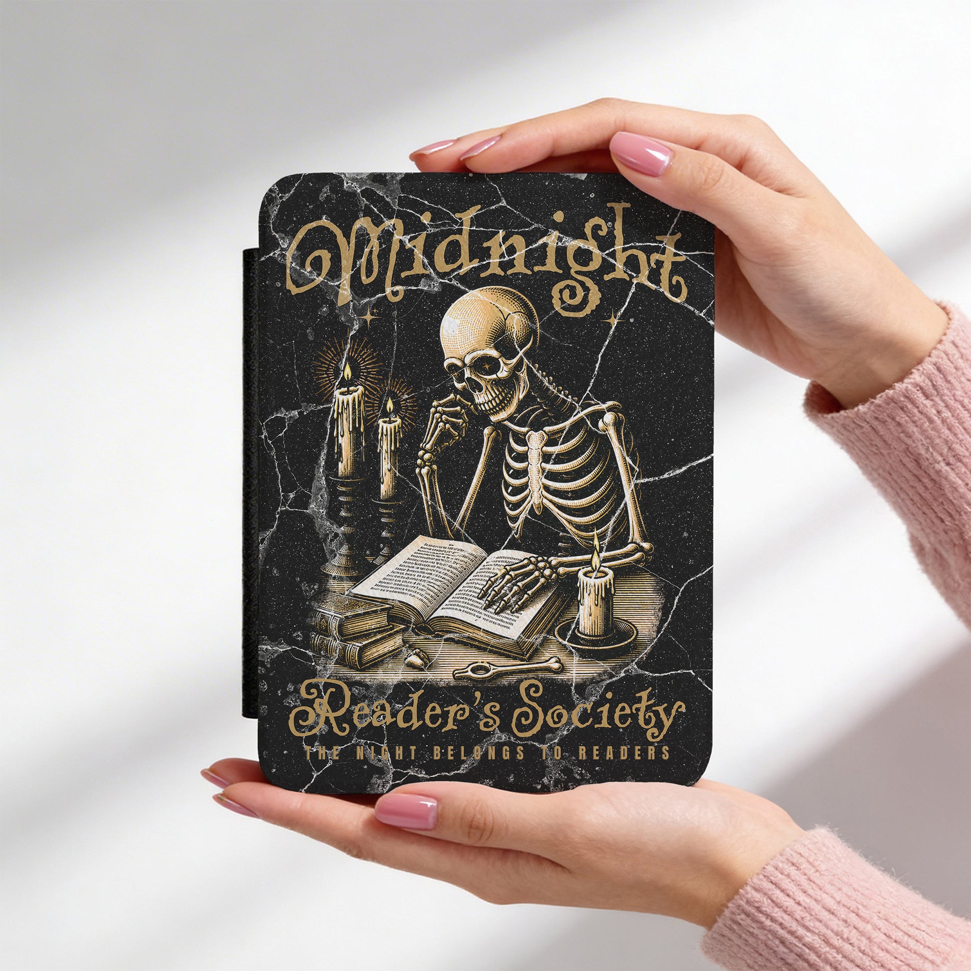 Kindle case with skeleton design and 'Midnight Reader's Society' text held by a person.