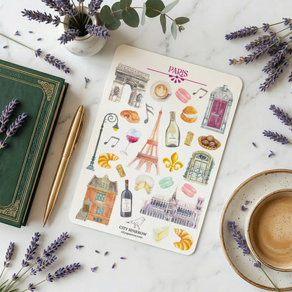 Sticker sheet with Paris-themed designs on a marble surface with lavender and a book.