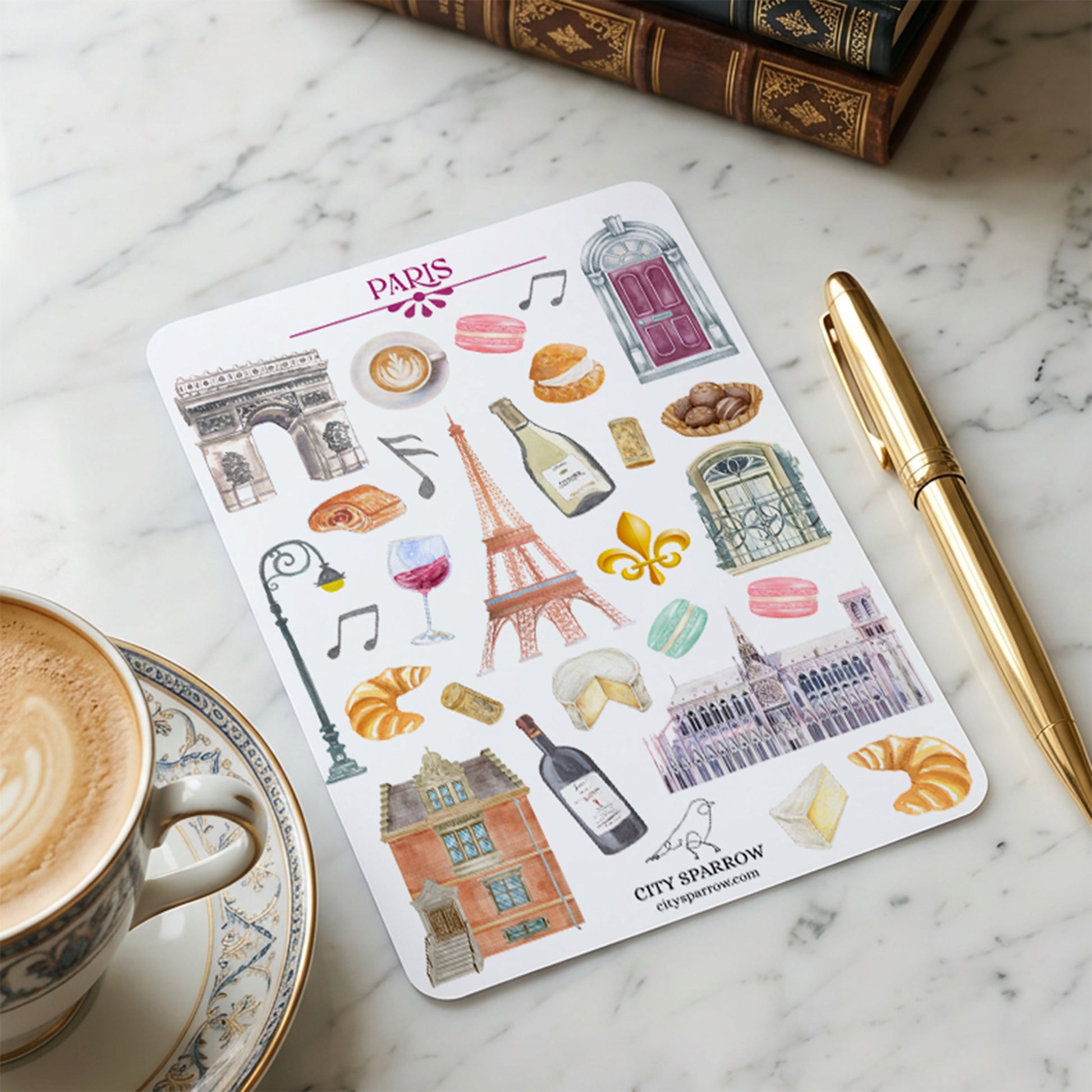 Sheet of Paris-themed stickers on a marble surface with a cup of coffee and pen.