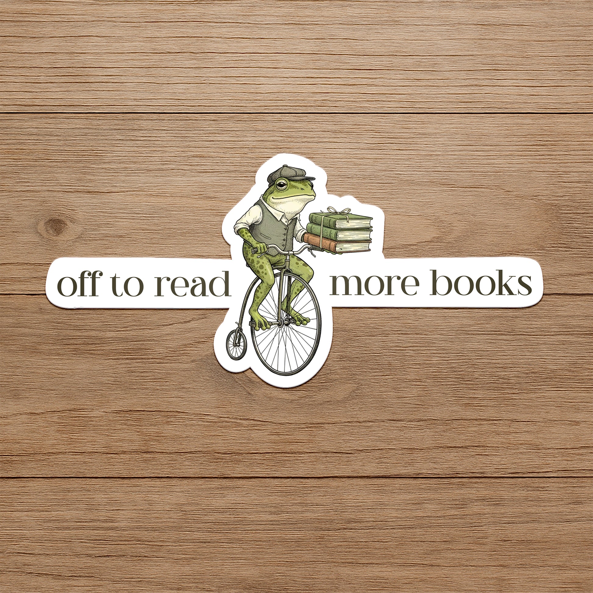 Frog on a bicycle with books, text 'off to read more books' on a wooden background