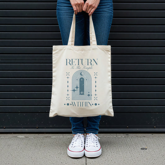 Person holding a tote bag with a blue temple design and text against a black slatted wall.