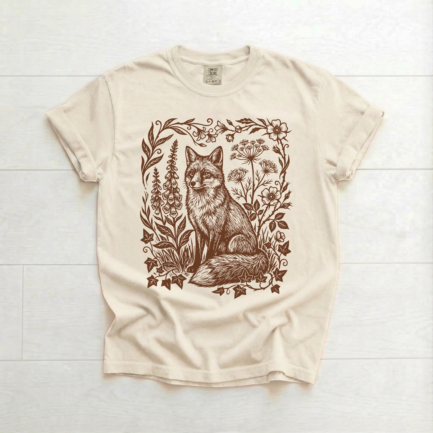 Beige t-shirt with a fox and floral design on a white wooden background