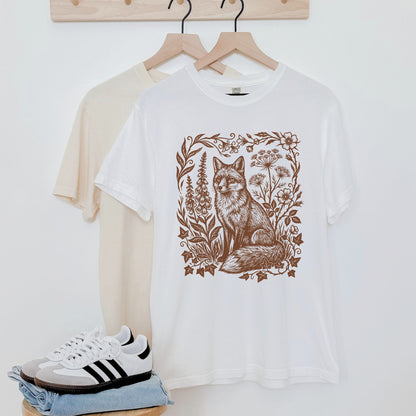 White t-shirt with a fox design on a hanger against a white wall.