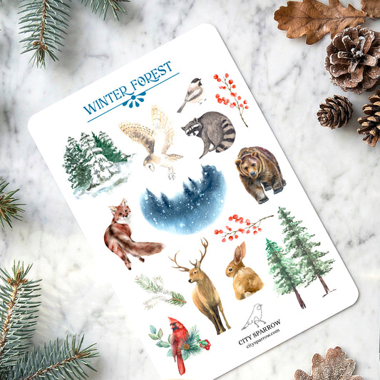 Sheet of winter-themed stickers featuring animals and nature elements on a marble surface with decorative items.